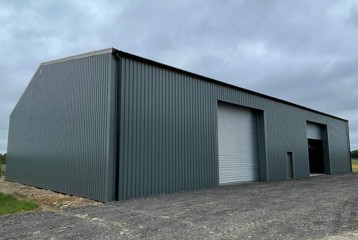 Exterior of green clad agricultural building with a double entrance and roller shutter doors