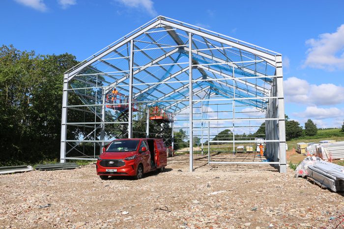 A front view of the steel frame in construction showing workers and vehicles